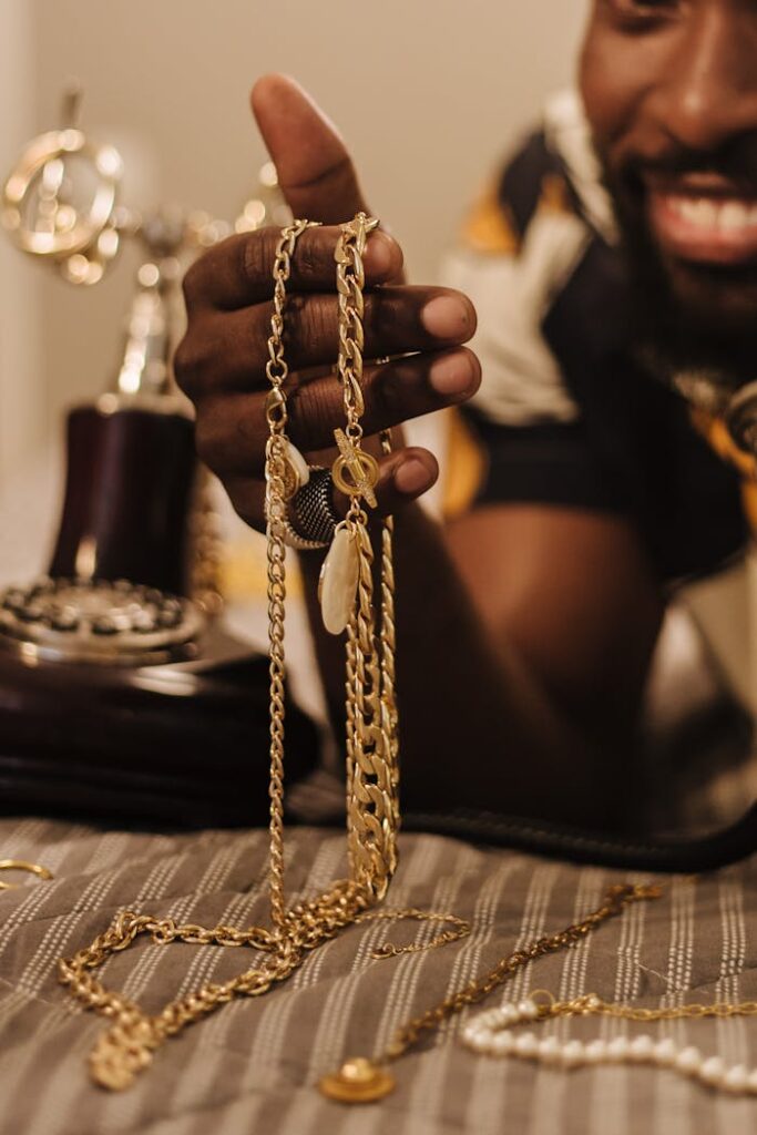 A smiling man holding intricate gold chains with a vintage phone nearby, creating a warm and luxurious ambiance.